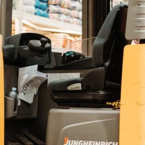 Interior of an empty forklift in a warehouse with stacks of products.